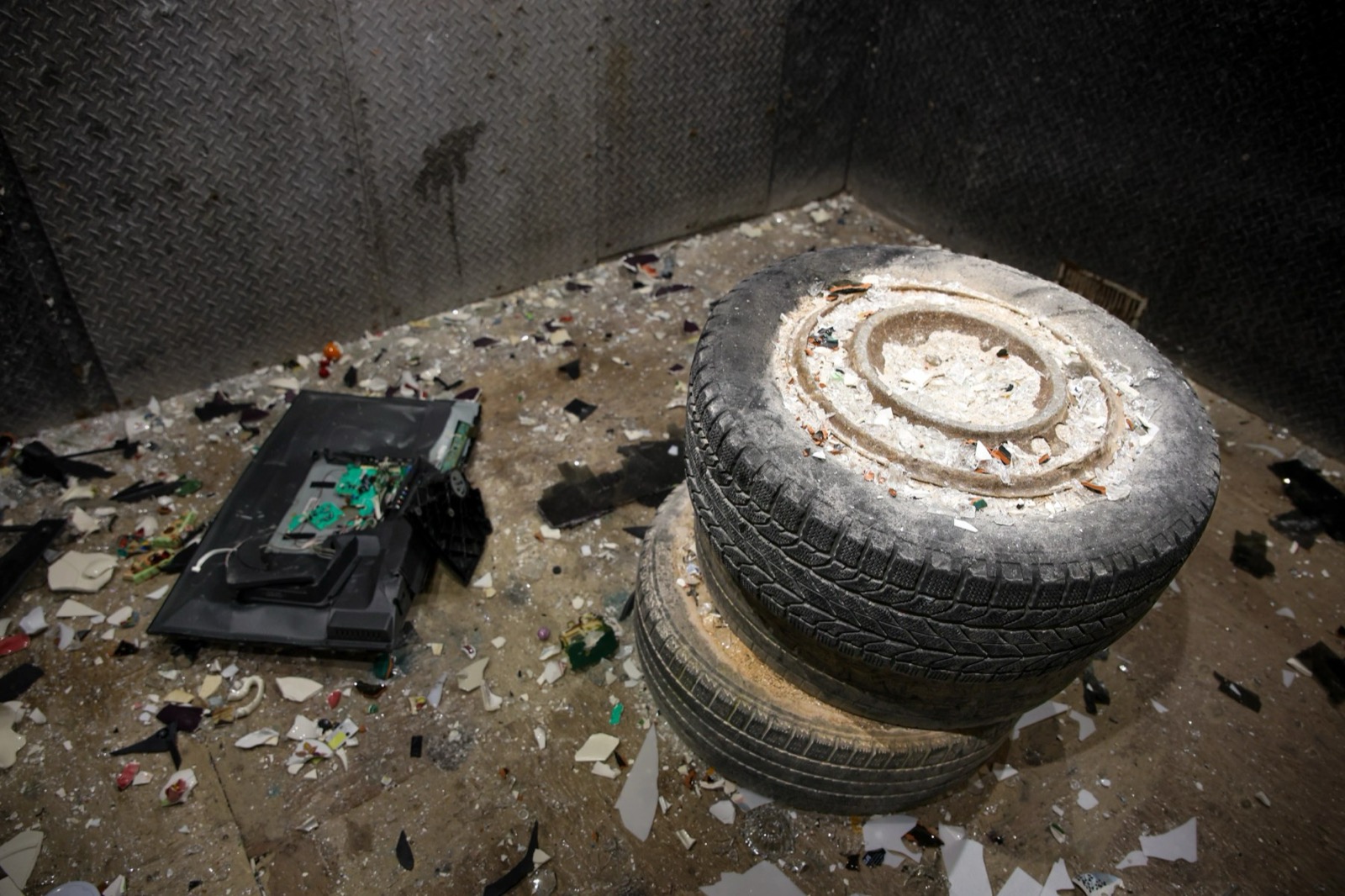 Inside the smash room: a shattered monitor and broken debris across the floor beside a stack of tires
